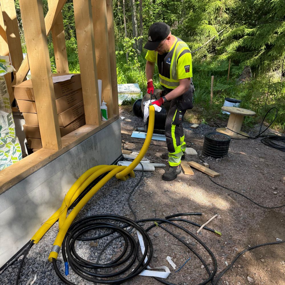 ViaCasa Oy – sähkökaapelin veto uudiskohteessa ViaCasan sähköasentaja vetää sähkökaapelia kelalta uudisrakennuksen runkoon. Etualalla kaapelikela ja taustalla rakenteilla oleva puurakenteinen kohde.
